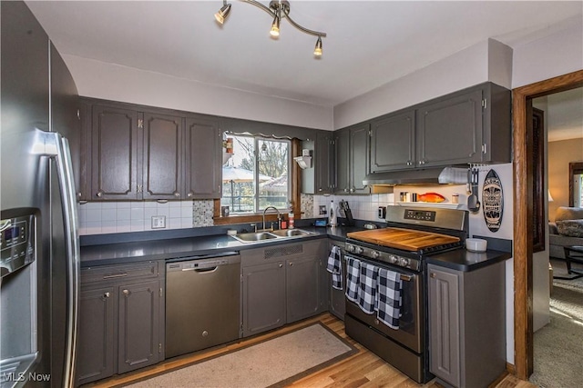 kitchen featuring stainless steel appliances, light hardwood / wood-style flooring, tasteful backsplash, and sink