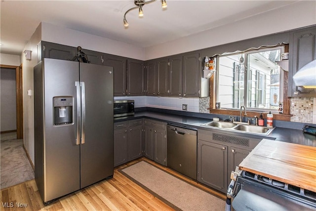 kitchen featuring stainless steel appliances, light hardwood / wood-style flooring, backsplash, and sink