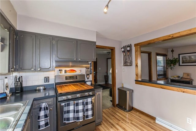 kitchen with tasteful backsplash, a baseboard radiator, light wood-type flooring, stainless steel range oven, and sink