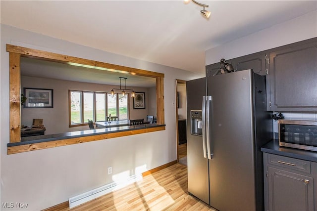 kitchen featuring light hardwood / wood-style floors, a baseboard heating unit, appliances with stainless steel finishes, and gray cabinetry