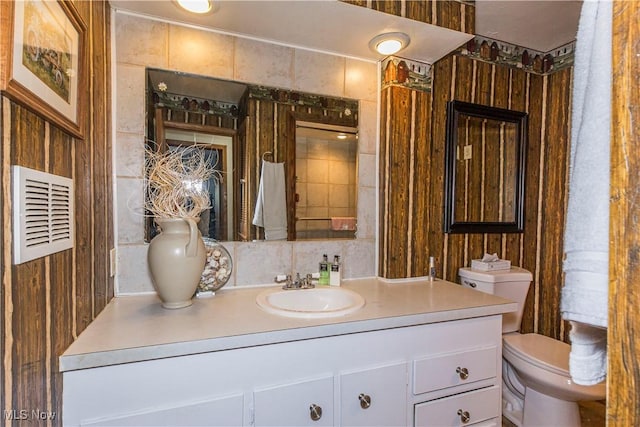 bathroom with toilet, wooden walls, and vanity