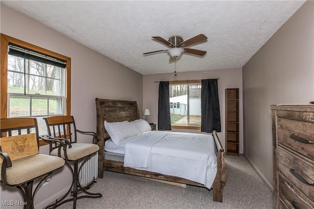 carpeted bedroom featuring a textured ceiling, ceiling fan, and multiple windows