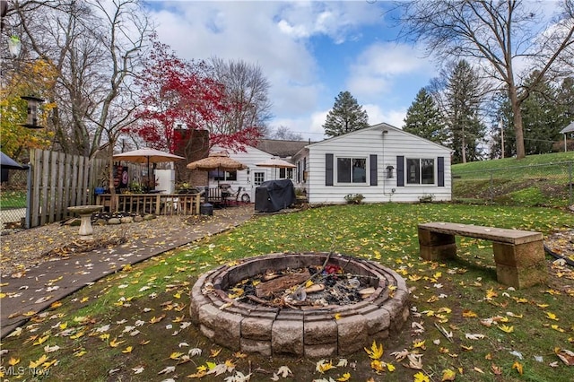 back of house featuring an outdoor fire pit and a lawn