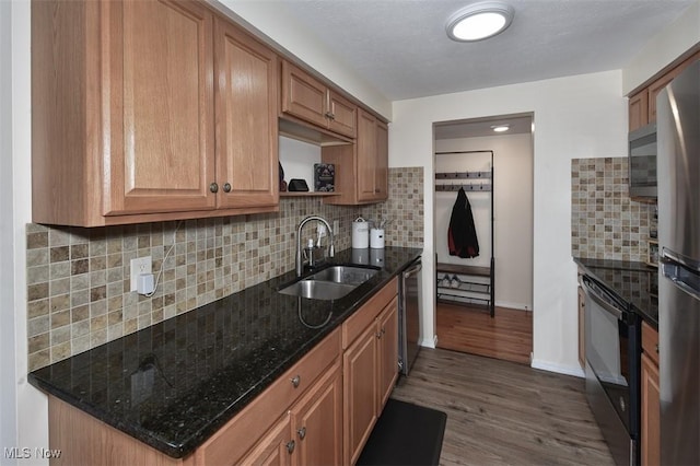 kitchen with decorative backsplash, sink, dark wood-type flooring, stainless steel appliances, and dark stone counters