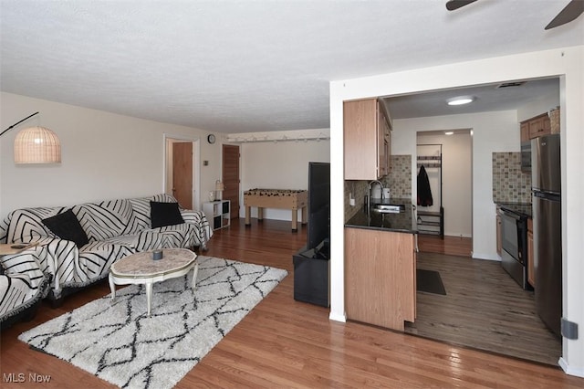 living room featuring ceiling fan, hardwood / wood-style flooring, and sink