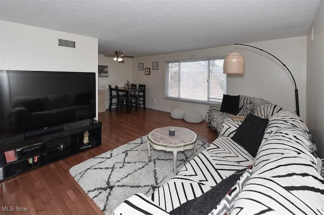 living room featuring ceiling fan and dark hardwood / wood-style floors