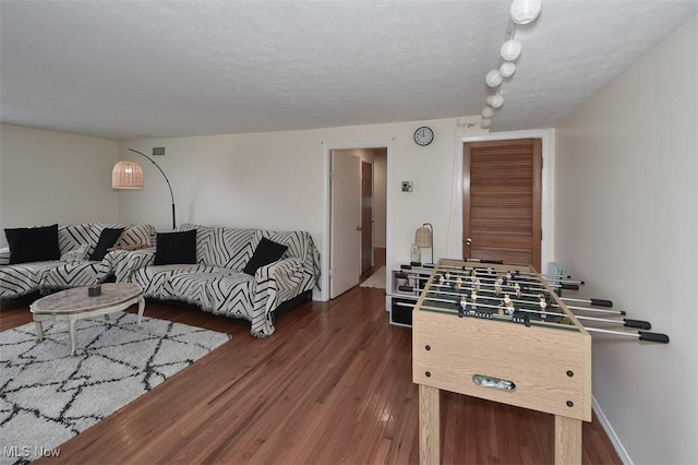 game room with a textured ceiling and dark hardwood / wood-style floors