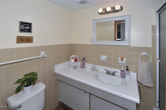 bathroom featuring toilet, vanity, and tile walls