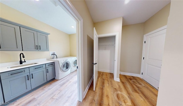 13430 Schreiber Rd, Valley View, OH 44125 - washroom featuring cabinet space, washer and dryer, a sink, baseboards, and light wood-type flooring