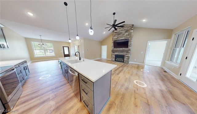 13430 Schreiber Rd, Valley View, OH 44125 - kitchen with ceiling fan with notable chandelier, a fireplace, light wood-style floors, a sink, and appliances with stainless steel finishes