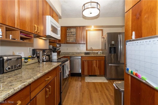 kitchen with sink, light wood-type flooring, light stone countertops, stainless steel appliances, and mail boxes