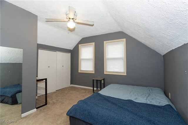 carpeted bedroom featuring ceiling fan, a closet, a textured ceiling, and lofted ceiling