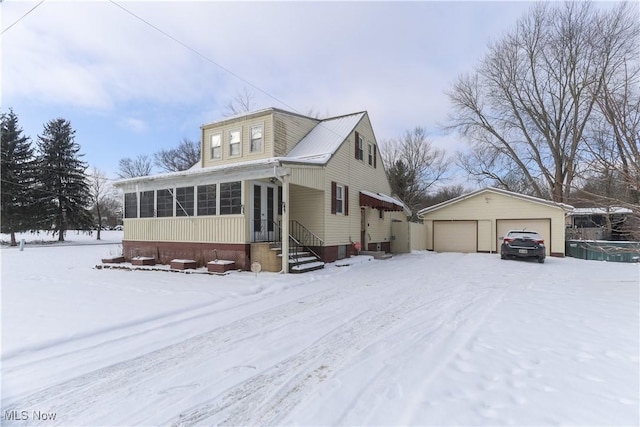 view of front of house featuring a garage, a sunroom, and an outdoor structure