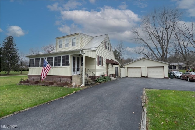 view of front of house featuring a garage, an outbuilding, and a front yard