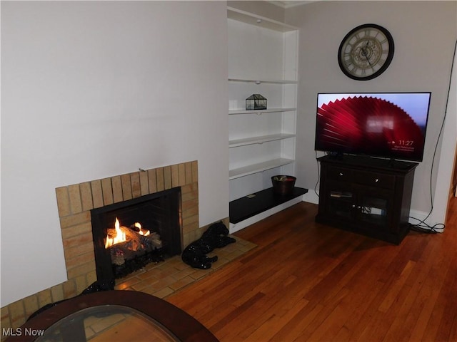 living room featuring a brick fireplace and dark wood-type flooring