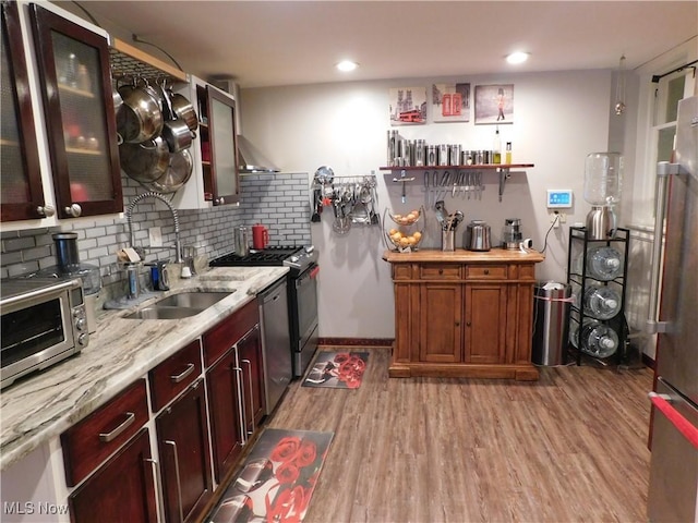 kitchen featuring stainless steel appliances, light hardwood / wood-style floors, sink, decorative backsplash, and light stone counters