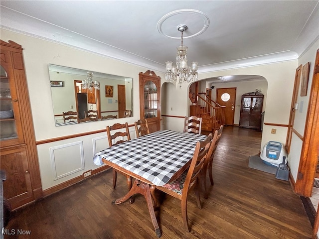 dining room with dark wood-type flooring, ornamental molding, and a notable chandelier