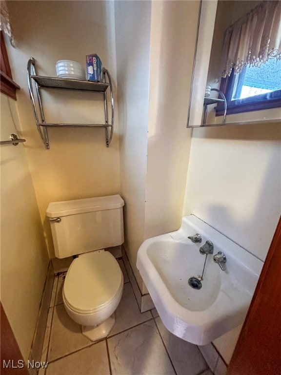 bathroom with toilet, tile patterned floors, and sink