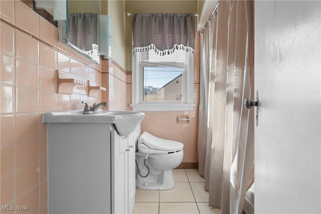 bathroom with toilet, tile walls, tile patterned floors, vanity, and curtained shower