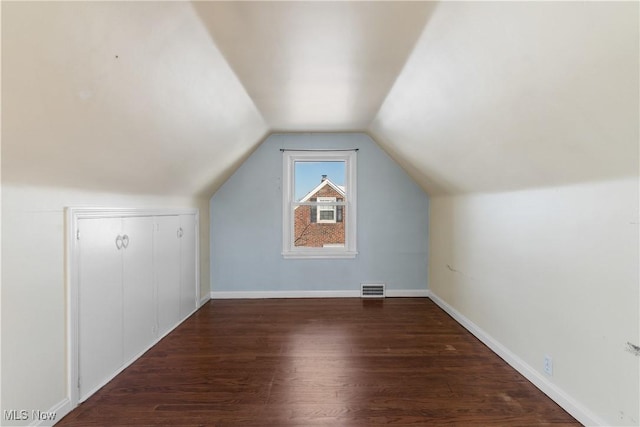 additional living space with dark hardwood / wood-style flooring and vaulted ceiling