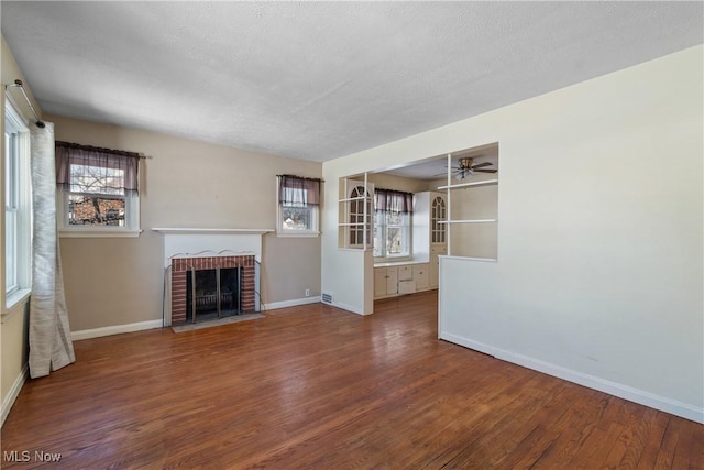 unfurnished living room with ceiling fan, hardwood / wood-style floors, a textured ceiling, and a fireplace