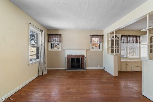 unfurnished living room with a fireplace, dark hardwood / wood-style flooring, and a textured ceiling