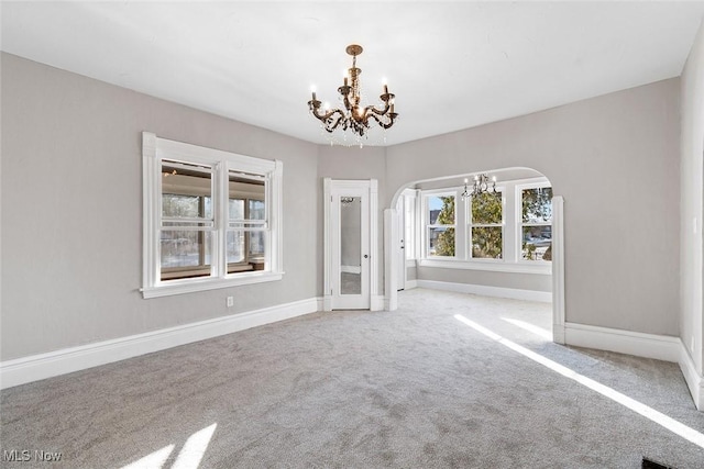 unfurnished room featuring carpet and an inviting chandelier