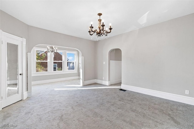 empty room featuring light carpet and an inviting chandelier