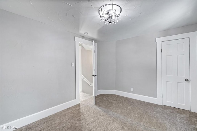 carpeted empty room with an inviting chandelier