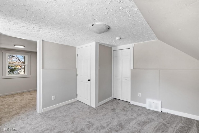 additional living space with lofted ceiling, light colored carpet, and a textured ceiling