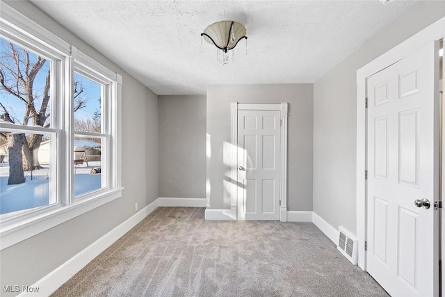 carpeted spare room with a textured ceiling