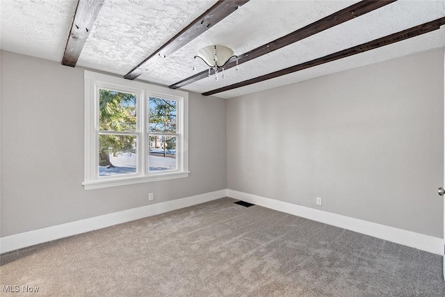 carpeted spare room featuring a textured ceiling and beamed ceiling