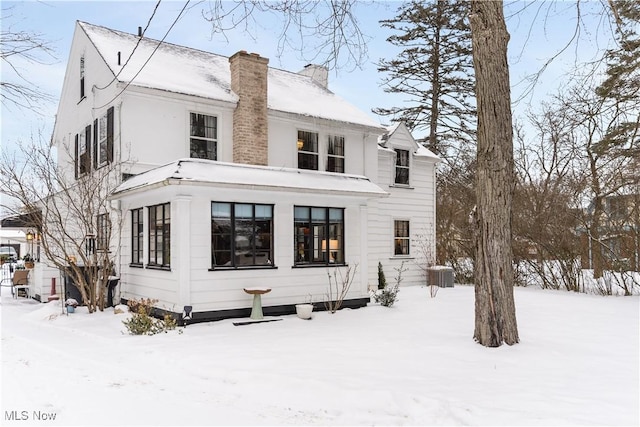 snow covered back of property with central AC