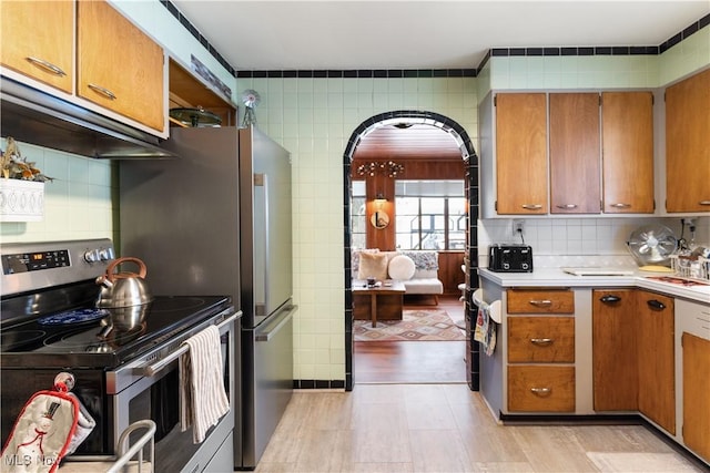 kitchen featuring tasteful backsplash, stainless steel electric range, and ventilation hood