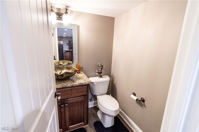 bathroom with toilet, hardwood / wood-style flooring, and vanity