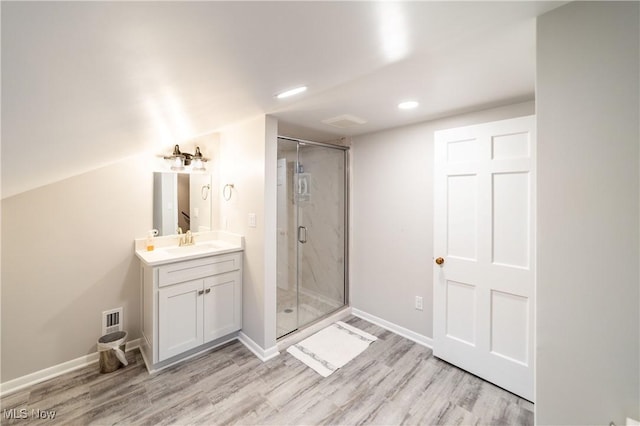 bathroom with vanity, vaulted ceiling, wood-type flooring, and walk in shower