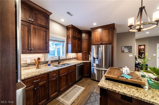 kitchen with stainless steel appliances, tasteful backsplash, dark wood-type flooring, pendant lighting, and sink