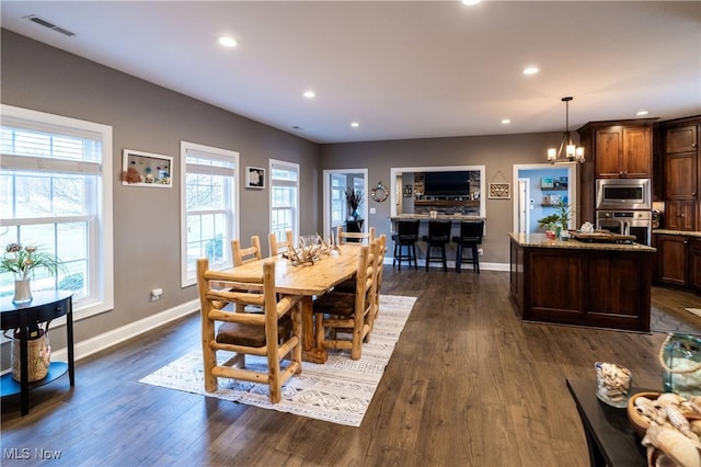 dining area with dark wood-type flooring and an inviting chandelier