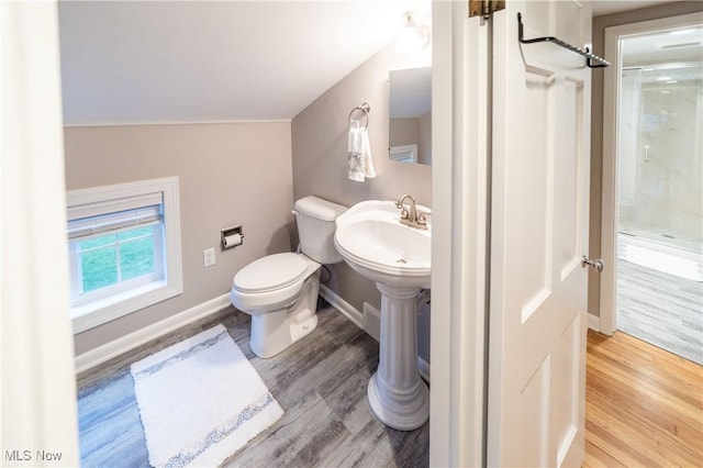 bathroom featuring wood-type flooring, toilet, walk in shower, and vaulted ceiling