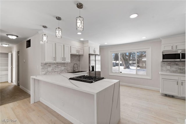 kitchen with decorative light fixtures, decorative backsplash, white cabinets, and stainless steel appliances