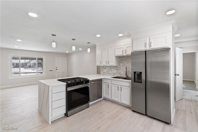 kitchen featuring decorative light fixtures, white cabinetry, stainless steel appliances, sink, and kitchen peninsula