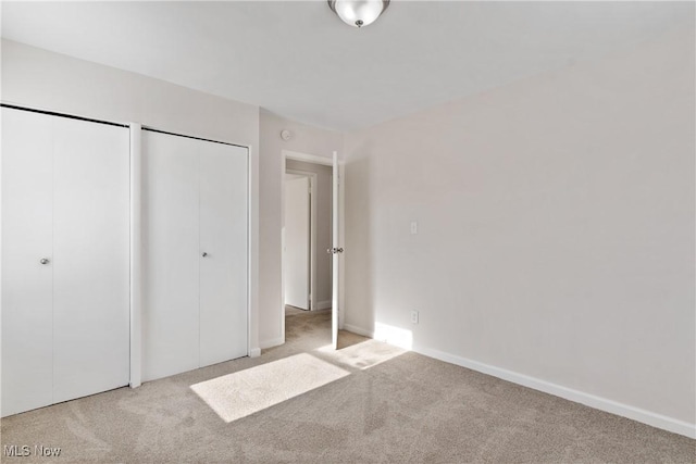 unfurnished bedroom with multiple closets and light colored carpet