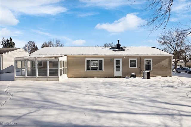 snow covered house featuring a sunroom