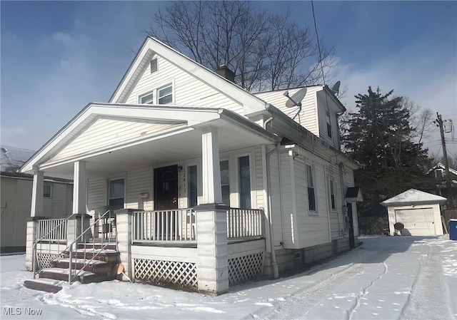 view of front of house featuring covered porch, a garage, and an outbuilding