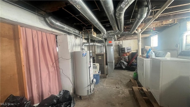 utility room with heating unit, water heater, and washer and dryer