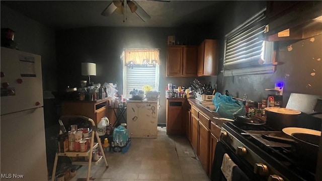 kitchen featuring ceiling fan, range, and white fridge