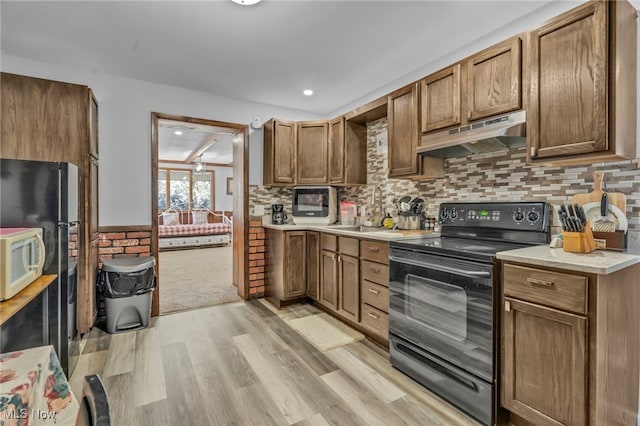 kitchen with black / electric stove, backsplash, light wood-type flooring, beam ceiling, and sink