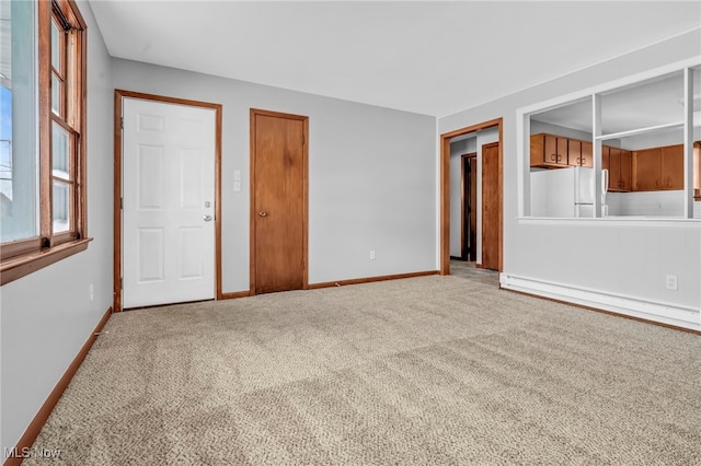 carpeted spare room with a baseboard heating unit