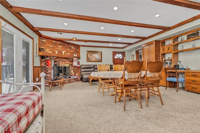 carpeted dining room featuring beam ceiling, a brick fireplace, and a wealth of natural light