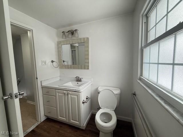 bathroom with hardwood / wood-style flooring, toilet, and vanity